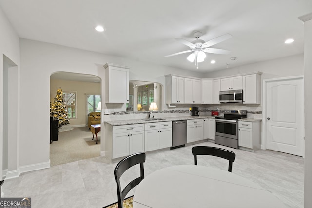 281 Hightower Lake Trl, Ball Ground, GA 30107 - kitchen with stainless steel appliances, arched walkways, ceiling fan, white cabinets, and recessed lighting