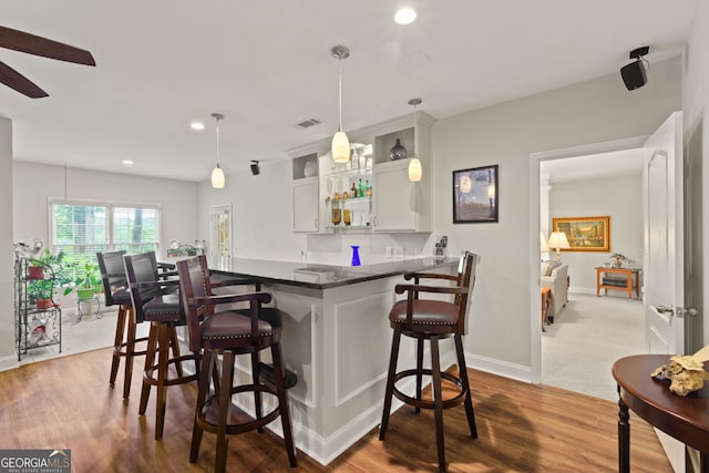 281 Hightower Lake Trl, Ball Ground, GA 30107 - kitchen with a kitchen bar, recessed lighting, dark countertops, white cabinetry, and a peninsula