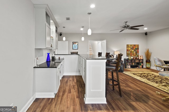 281 Hightower Lake Trl, Ball Ground, GA 30107 - kitchen featuring dark countertops, a peninsula, dark wood finished floors, a breakfast bar, and recessed lighting