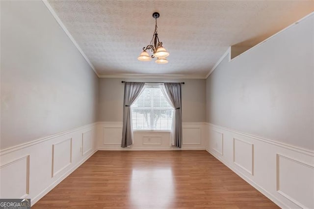 738 Baskins, Winder, GA 30680 - empty room with a chandelier, crown molding, a wainscoted wall, light wood finished floors, and a textured ceiling