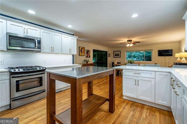 3300 Wiltshire Dr, Avondale Estates, GA 30002 - kitchen featuring appliances with stainless steel finishes, light countertops, light wood-type flooring, ceiling fan, and a peninsula