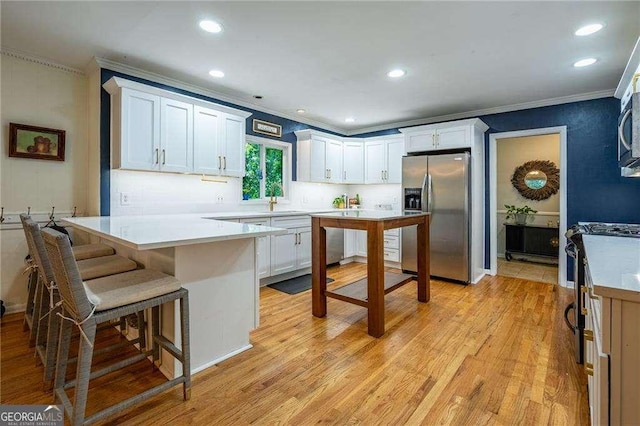 3300 Wiltshire Dr, Avondale Estates, GA 30002 - kitchen featuring stainless steel appliances, ornamental molding, a peninsula, white cabinets, and a breakfast bar area