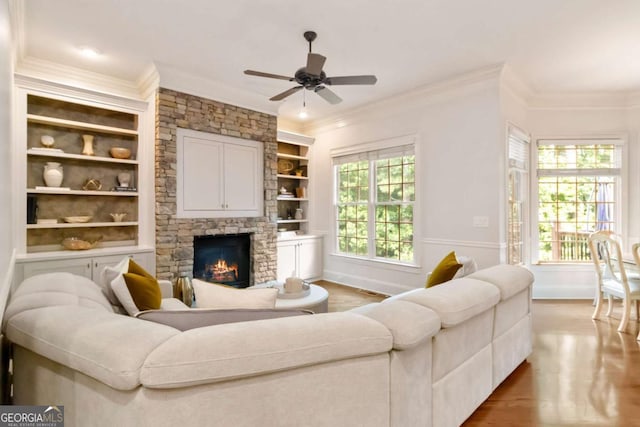 2230 Cambridge Hill Ct, Dacula, GA 30019 - living area featuring crown molding, wood finished floors, a stone fireplace, ceiling fan, and built in features
