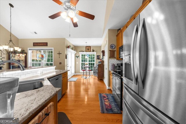 221 Timber Ridge Dr, Clarkesville, GA 30523 - kitchen featuring appliances with stainless steel finishes, brown cabinets, light wood-style floors, hanging light fixtures, and a chandelier