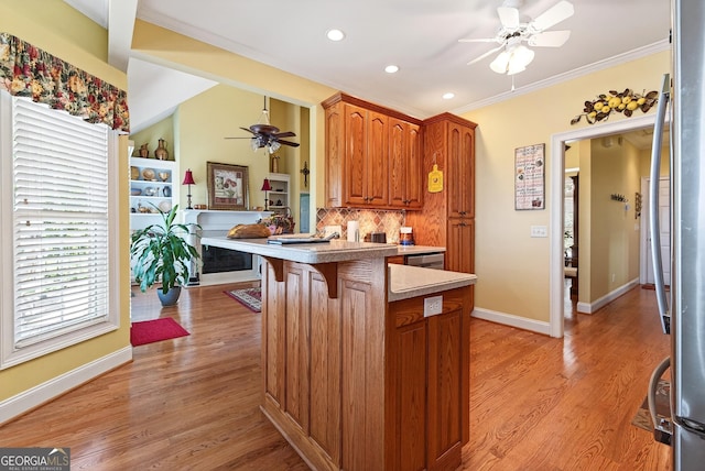 865 Laurel Ridge Rd, Cleveland, GA 30528 - kitchen featuring a ceiling fan, a peninsula, a breakfast bar area, brown cabinetry, and ornamental molding