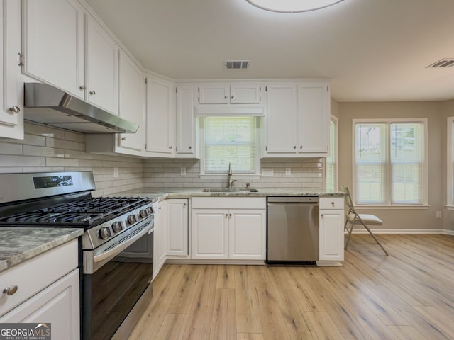 1904 Watercrest Cir, Lawrenceville, GA 30043 - kitchen featuring stainless steel appliances, under cabinet range hood, white cabinetry, light wood finished floors, and tasteful backsplash