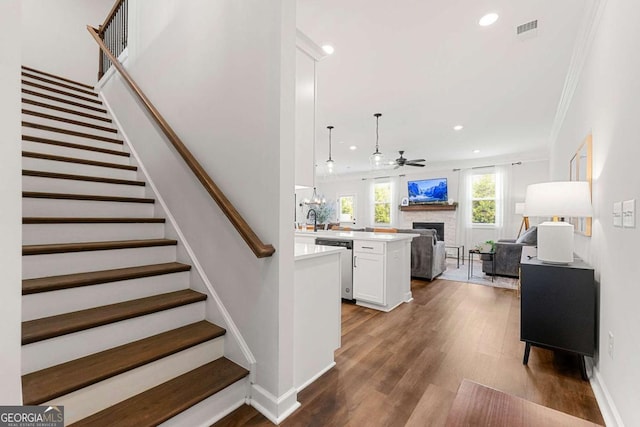 1316 Willamette Way, Marietta, GA 30008 - stairway featuring a fireplace, a ceiling fan, recessed lighting, wood finished floors, and ornamental molding