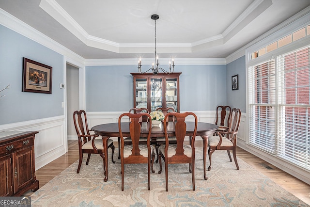 351 Prestbury Ct, Suwanee, GA 30024 - dining room featuring a raised ceiling, light wood finished floors, a chandelier, crown molding, and a wainscoted wall
