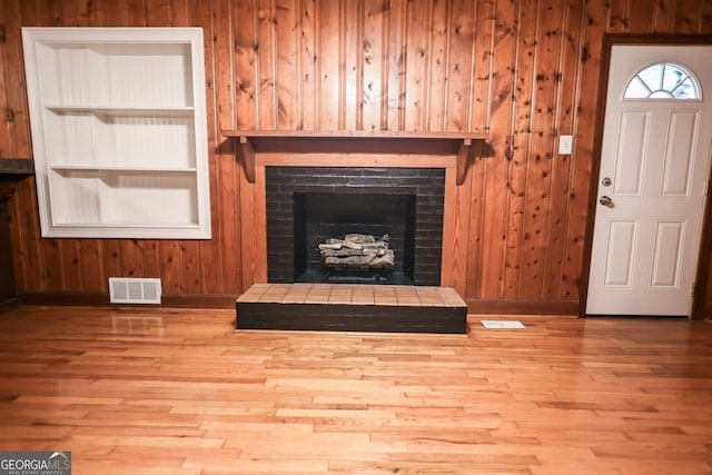 500 Holmes St, Barnesville, GA 30204 - unfurnished living room with wood finished floors, a fireplace with raised hearth, and wood walls
