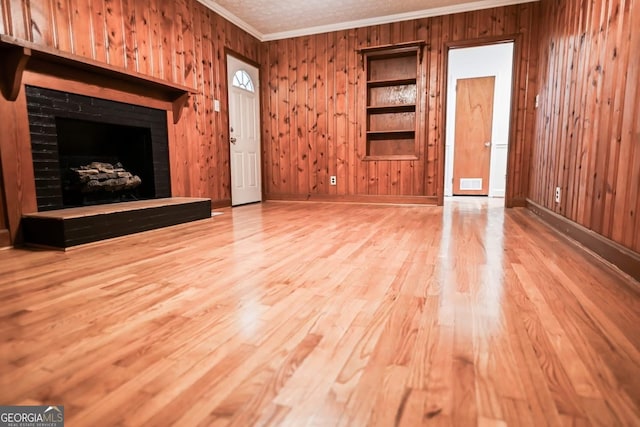500 Holmes St, Barnesville, GA 30204 - unfurnished living room featuring ornamental molding, wooden walls, wood finished floors, and a fireplace