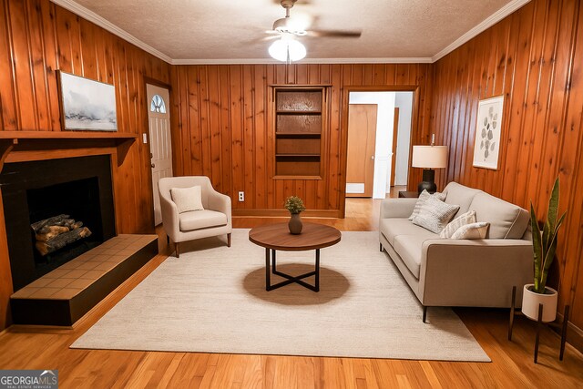 500 Holmes St, Barnesville, GA 30204 - living area with crown molding, wooden walls, a tile fireplace, wood finished floors, and ceiling fan