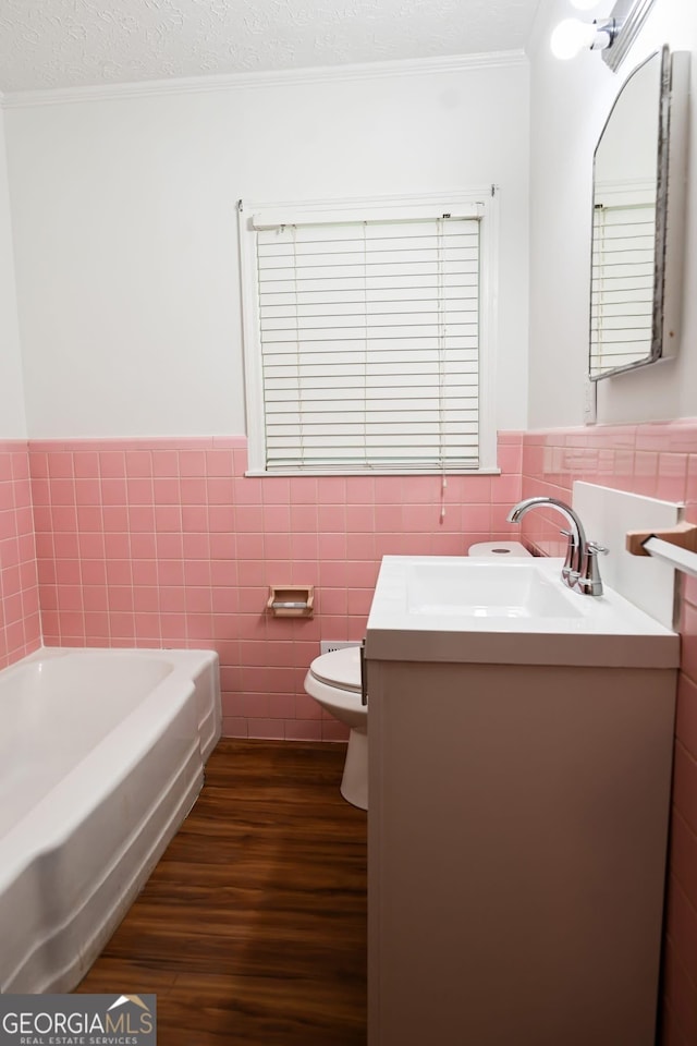 500 Holmes St, Barnesville, GA 30204 - full bath with tile walls, vanity, crown molding, wood finished floors, and a garden tub