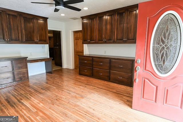 500 Holmes St, Barnesville, GA 30204 - kitchen featuring ceiling fan, built in desk, light wood-style floors, dark brown cabinetry, and dark countertops