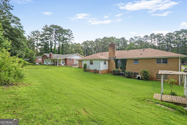 3563 Carriage Way, East Point, GA 30344 - back of house featuring a yard, a chimney, brick siding, and view of scattered trees