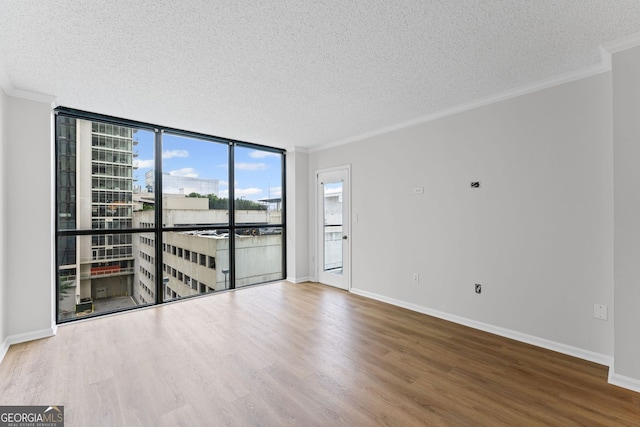 1280 W Peachtree St NW Unit 808, Atlanta, GA 30309 - unfurnished room with crown molding, a textured ceiling, wood finished floors, and a wall of windows