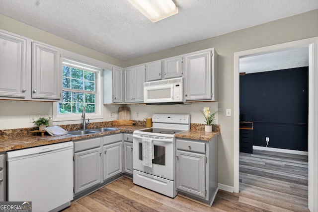 106 Ivy Ct, Lagrange, GA 30241 - kitchen featuring white appliances, light wood-style flooring, gray cabinetry, a textured ceiling, and dark countertops