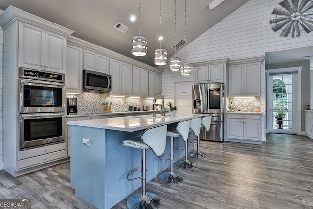682 Tanglewood Ln, Ellijay, GA 30540 - kitchen with appliances with stainless steel finishes, wood finished floors, tasteful backsplash, a kitchen island with sink, and a kitchen bar