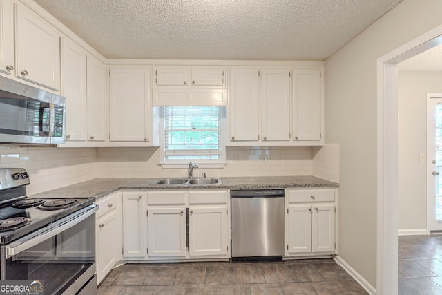 3110 Ashly Cove Ln, Snellville, GA 30078 - kitchen featuring appliances with stainless steel finishes, white cabinetry, light stone counters, backsplash, and a textured ceiling