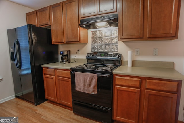 691 Walnut Woods Dr, Braselton, GA 30517 - kitchen featuring black appliances, under cabinet range hood, light wood finished floors, light countertops, and brown cabinetry