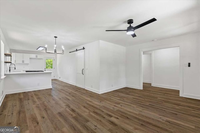 1400 N Ave NW, Atlanta, GA 30318 - unfurnished living room featuring a barn door, dark wood-style floors, a ceiling fan, and a chandelier