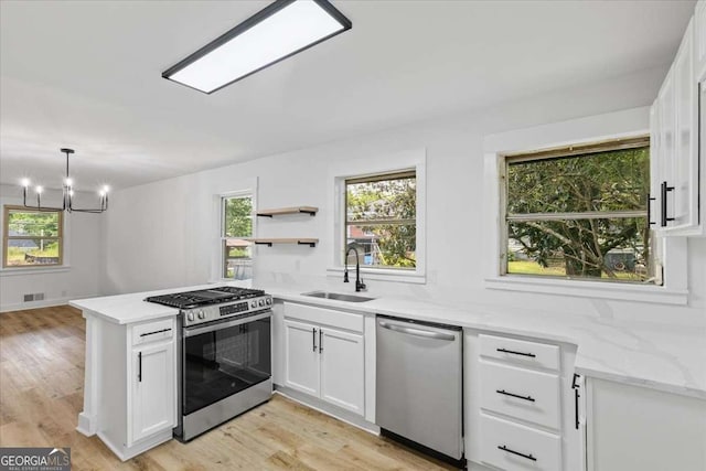 1400 N Ave NW, Atlanta, GA 30318 - kitchen with stainless steel appliances, a peninsula, white cabinets, a chandelier, and light wood-type flooring