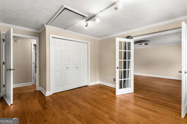 115 Biscayne Dr NW Unit E3, Atlanta, GA 30309 - unfurnished bedroom with attic access, wood finished floors, a closet, track lighting, and a textured ceiling