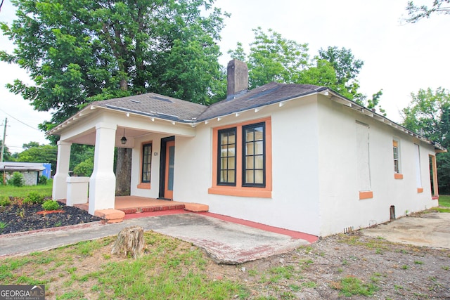 826 W Grenada Ter, Macon, GA 31206 - view of front facade with a porch, stucco siding, a chimney, and roof with shingles