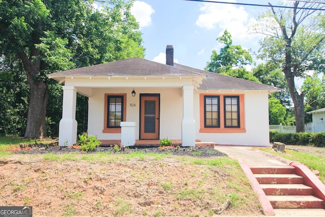826 W Grenada Ter, Macon, GA 31206 - view of front facade with covered porch, a shingled roof, a chimney, and stucco siding