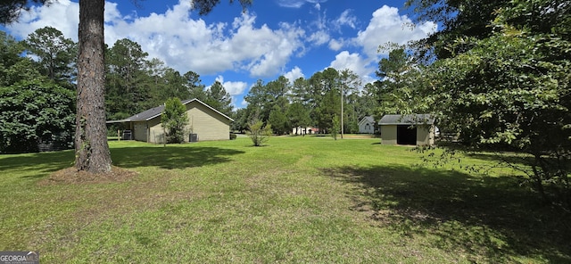 467 Witherington Cir, East Dublin, GA 31027 - view of grassy yard featuring a storage unit, a garage, and view of wooded area