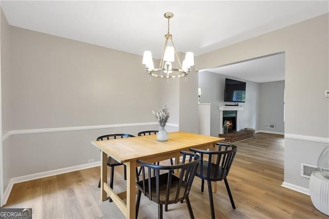 410 Sheringham Ct, Roswell, GA 30076 - dining space with a chandelier, wood finished floors, and a warm lit fireplace