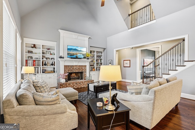 2470 Green Mountain Dr, Braselton, GA 30517 - living room featuring high vaulted ceiling, dark wood-style flooring, ceiling fan, a brick fireplace, and stairway