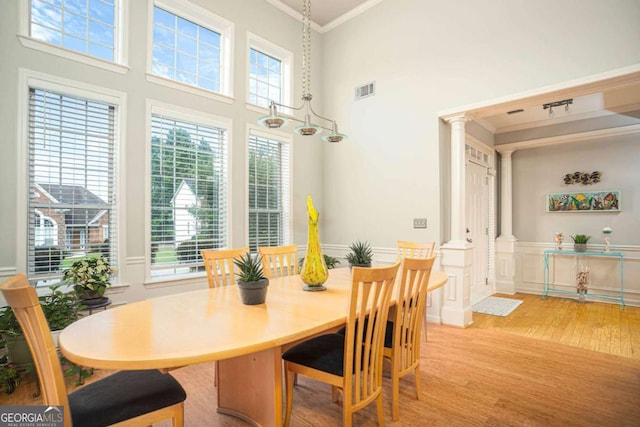 1511 Rocky Knoll Ln, Dacula, GA 30019 - dining room with light wood-style floors, ornate columns, ornamental molding, a high ceiling, and a wainscoted wall