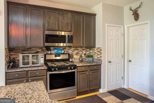 1511 Rocky Knoll Ln, Dacula, GA 30019 - kitchen featuring stainless steel appliances, dark brown cabinetry, backsplash, and light stone counters