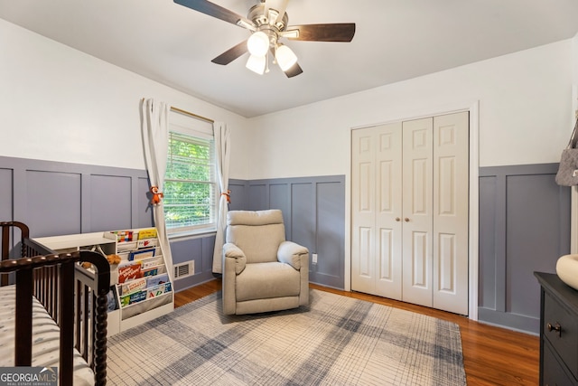2163 Medfield Trl NE, Chamblee, GA 30345 - bedroom featuring a decorative wall, wainscoting, wood finished floors, ceiling fan, and a nursery area