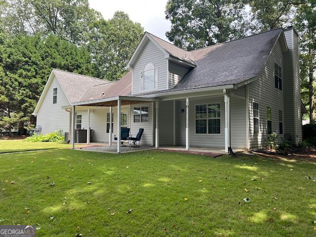 149 Crown Oaks Dr, Stockbridge, GA 30281 - back of property featuring a lawn, a chimney, and a patio