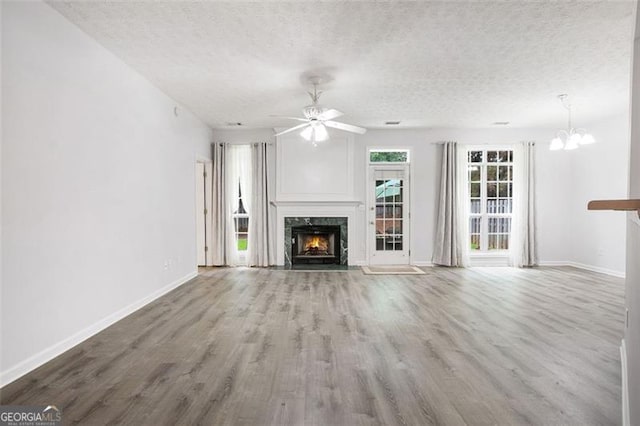 13440 Avensong Xing, Alpharetta, GA 30004 - unfurnished living room featuring a premium fireplace, wood finished floors, a textured ceiling, ceiling fan, and a chandelier