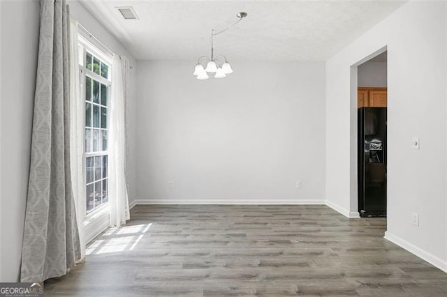 13440 Avensong Xing, Alpharetta, GA 30004 - unfurnished dining area featuring a chandelier, wood finished floors, and a textured ceiling