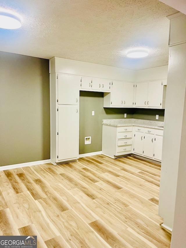 935 Mccall Rd, Macon, GA 31217 - kitchen featuring a textured ceiling, light wood-style flooring, white cabinetry, and light countertops