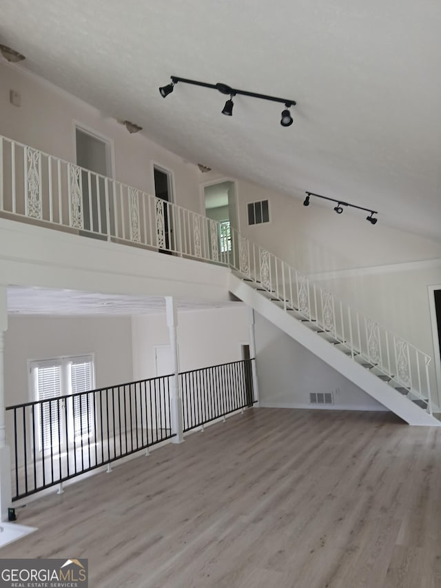 6985 Butner Rd, South Fulton, GA 30349 - unfurnished living room with track lighting, wood finished floors, and a towering ceiling