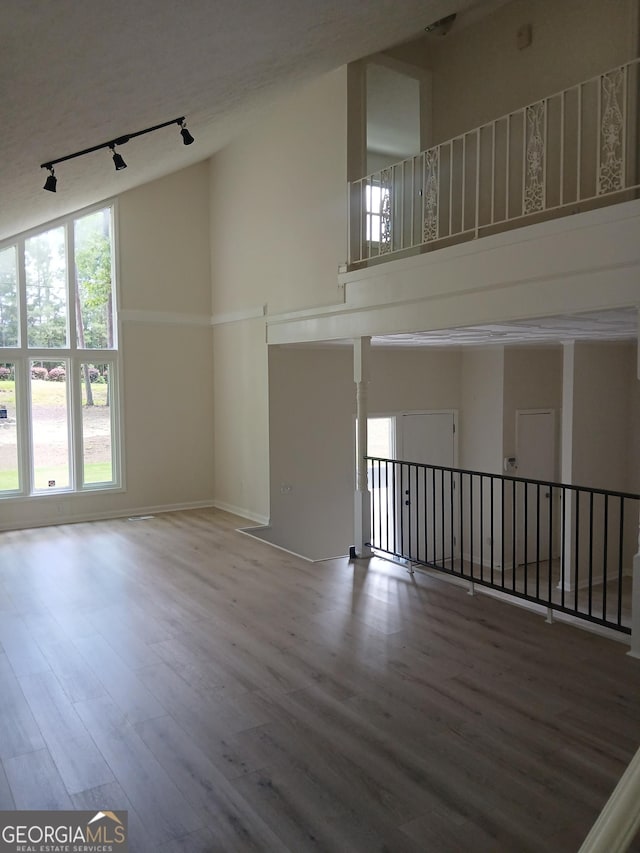 6985 Butner Rd, South Fulton, GA 30349 - unfurnished living room featuring track lighting, wood finished floors, and high vaulted ceiling