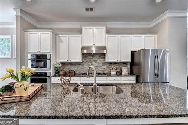 711 Topsail Ln, Alpharetta, GA 30005 - kitchen featuring stainless steel appliances, under cabinet range hood, white cabinetry, dark stone counters, and crown molding