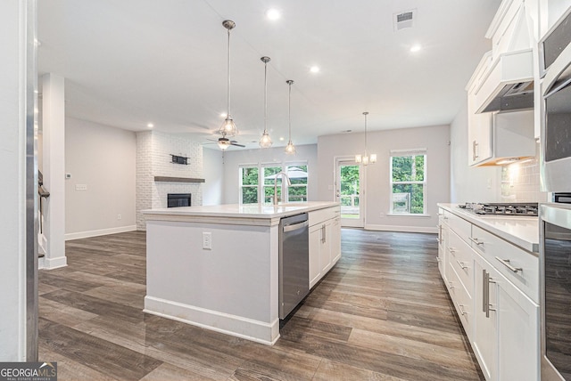 129 Academy Ln, Canton, GA 30114 - kitchen featuring appliances with stainless steel finishes, a fireplace, ceiling fan, a center island with sink, and open floor plan