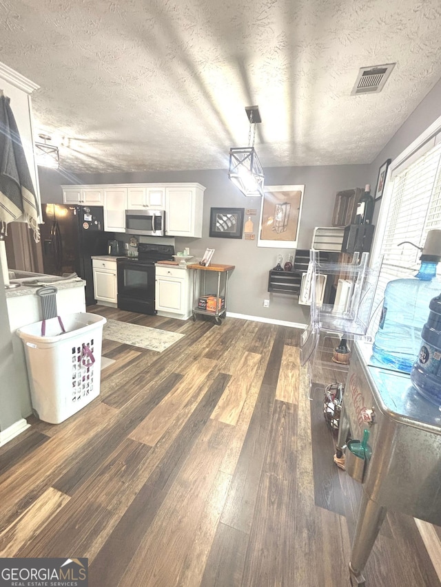 214 Sugar Hill Ct, Jackson, GA 30233 - kitchen with stainless steel microwave, black range with electric stovetop, white cabinetry, dark wood-style flooring, and a textured ceiling