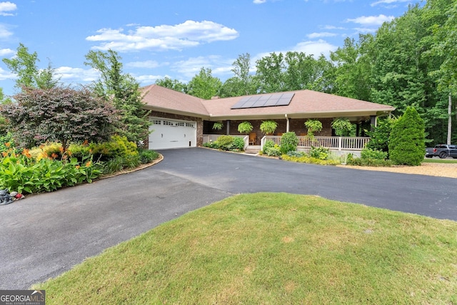 1572 Azalea Dr, Lawrenceville, GA 30043 - view of front of home featuring covered porch, driveway, solar panels, an attached garage, and a front yard