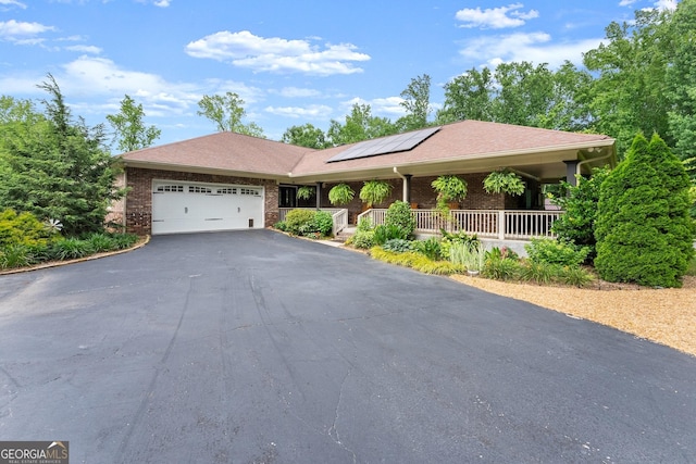 1572 Azalea Dr, Lawrenceville, GA 30043 - single story home with a porch, driveway, a garage, solar panels, and brick siding