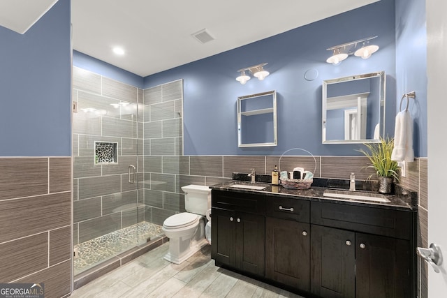 1572 Azalea Dr, Lawrenceville, GA 30043 - bathroom with tile walls, double vanity, a stall shower, wood finished floors, and a wainscoted wall