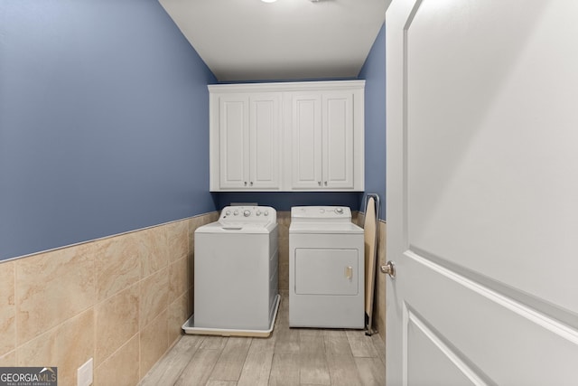 1572 Azalea Dr, Lawrenceville, GA 30043 - laundry room featuring washing machine and dryer, tile walls, a wainscoted wall, cabinet space, and light wood-type flooring