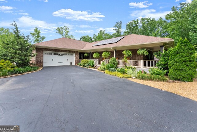 1572 Azalea Dr, Lawrenceville, GA 30043 - single story home with a porch, driveway, a garage, solar panels, and brick siding