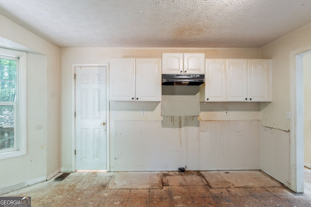 3930 Pine Tree Ln, Gainesville, GA 30501 - kitchen with under cabinet range hood, white cabinetry, and a textured ceiling