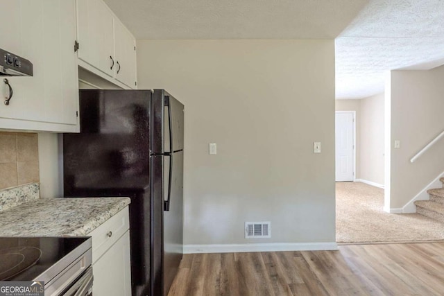 5207 Shawn Ln, Stone Mountain, GA 30088 - kitchen with wood finished floors, freestanding refrigerator, white cabinets, and decorative backsplash